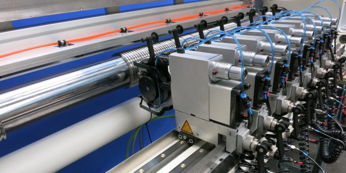 Auf dem Bild ist ein automatisches Schneidsystem für den Scherenschnitt von DIENES. Ebenfalls zu erkennen sind dabei die Adapter mit denen die Messerhalter an der Schiene befestigt sind.